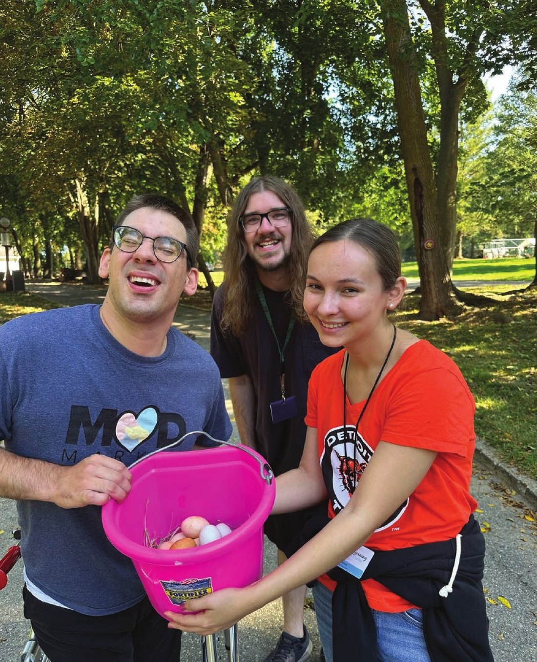 Three Living and Learning members laughing together with a bucket of eggs from the campus farm