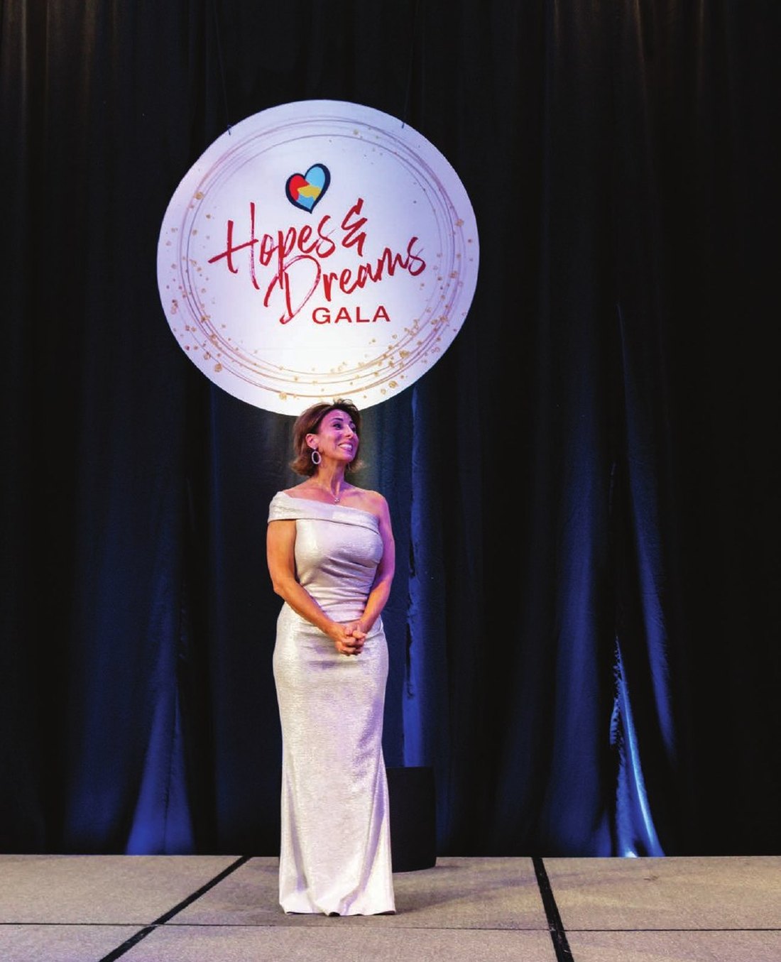 Rachelle Vartanian on stage beneath the Hopes and Dreams Gala sign